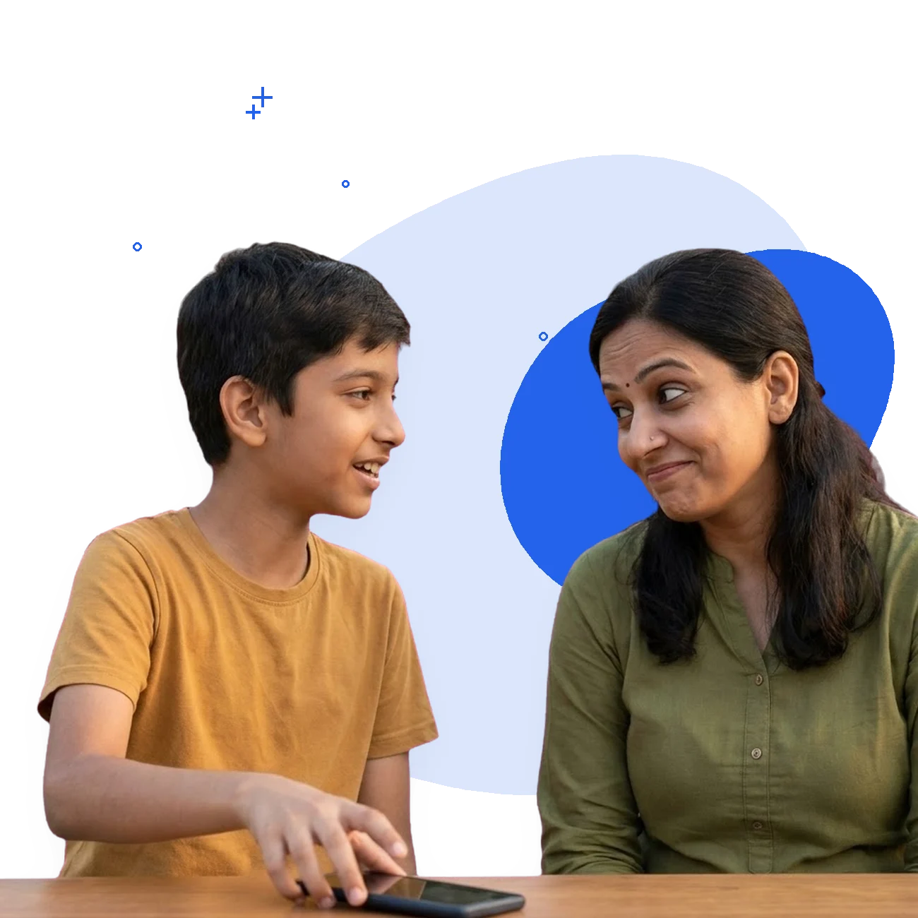 A boy of eleven has put his phone face-down on the table and turned to talk to his mother, who is listening, amused.